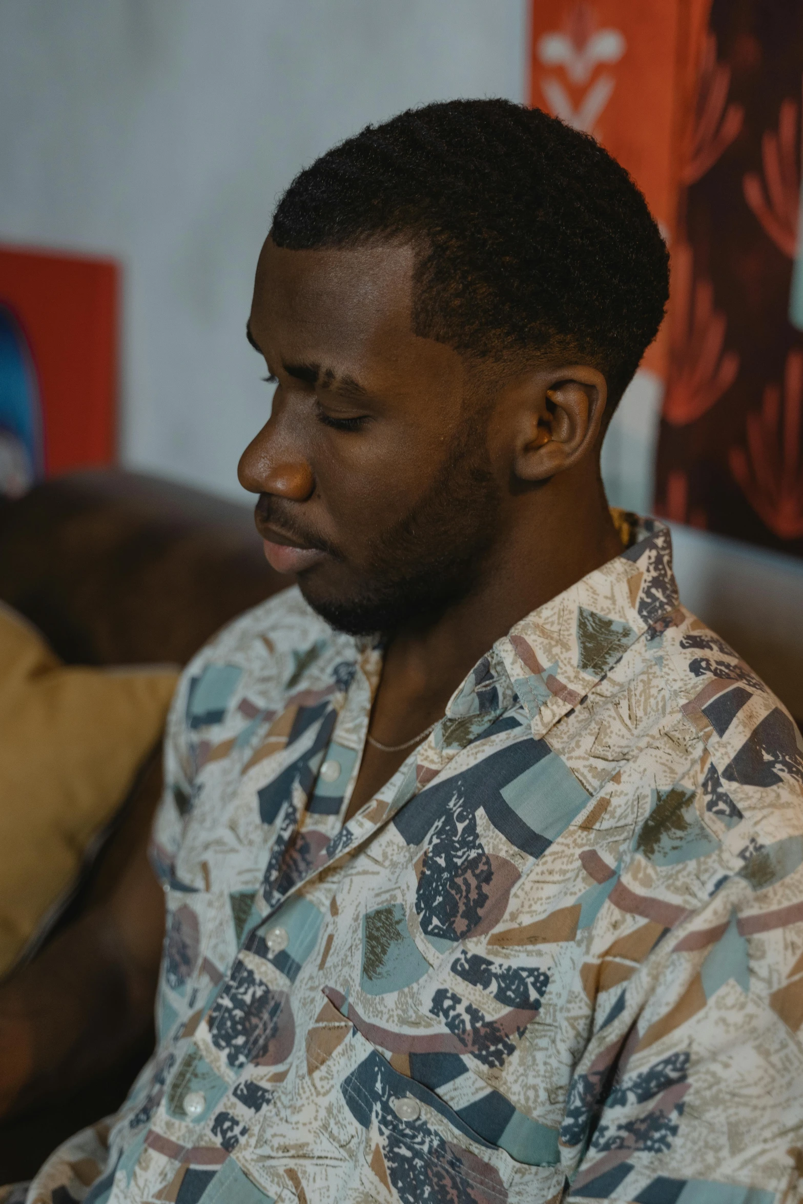 a man sitting on a couch using a laptop, an album cover, trending on pexels, black arts movement, hawaiian shirt, pensive expression, ( ( theatrical ) ), patterned