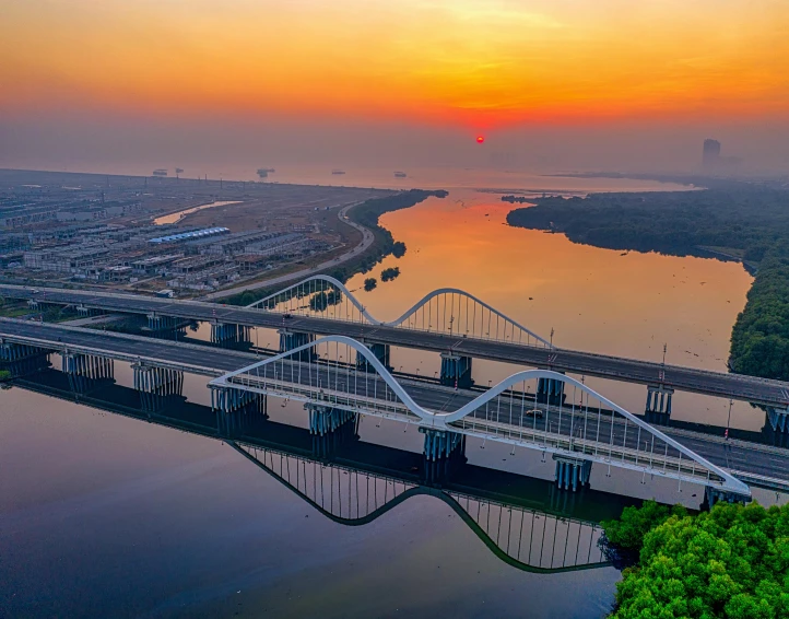 a bridge over a body of water with a sunset in the background, pexels contest winner, happening, arab ameera al taweel, hd aerial photography, giant river, high quality print