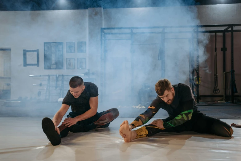 a couple of men sitting on top of a floor, in fighter poses, charli bowater and artgeem, profile image, stretching to walls