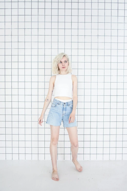 a woman standing in front of a checkered wall, an album cover, inspired by Elsa Bleda, unsplash, realism, denim short pants, very very pale blond hair, white background : 3, croptop