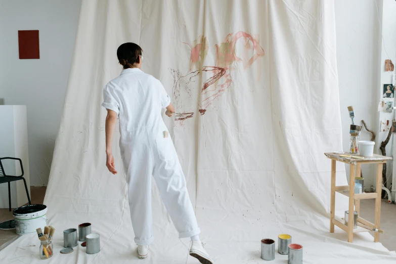 a man that is standing in front of a painting, pexels contest winner, action painting, wearing white pajamas, studio backdrop, wearing a labcoat, art materials