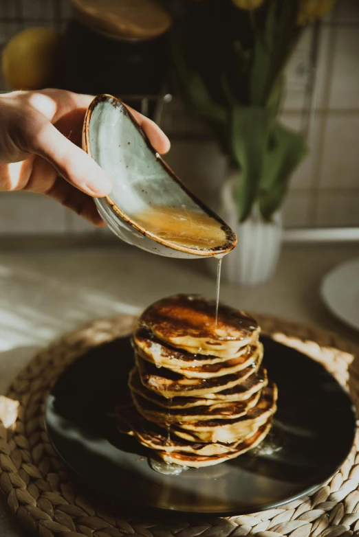 a person pouring syrup onto a stack of pancakes, by Julia Pishtar, pexels contest winner, renaissance, made of glazed, manuka, black, eco