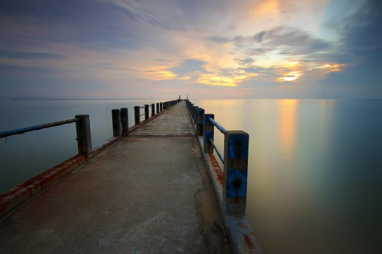 a pier stretching out into the ocean at sunset, by Brad Holland, thawan duchanee, 4k photo”, grey, multicoloured