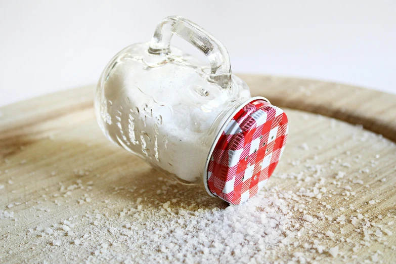 a jar of salt sitting on top of a wooden cutting board, pixabay, photorealism, covered in white flour, picnic, glazed, miniature product photo