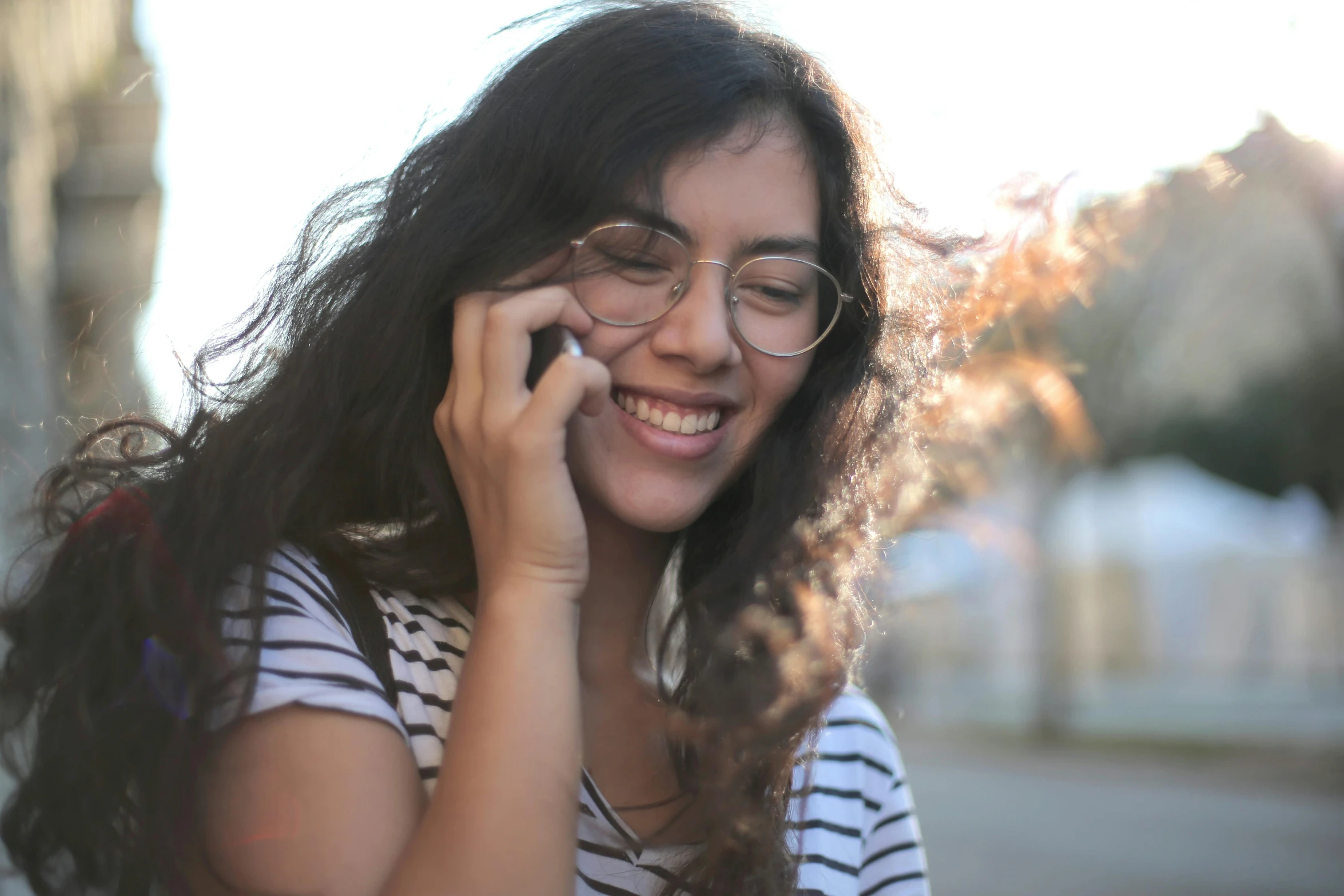 a woman with glasses talking on a cell phone, a photo, trending on pexels, smiling girl, olive skinned, 1 4 5 0, flattened