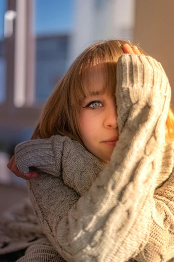 a little girl sitting on top of a bed next to a window, trending on pexels, romanticism, wearing casual sweater, hands shielding face, portrait of women embracing, warm shading