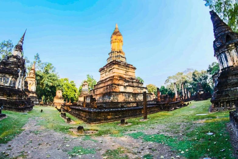 a group of buildings sitting on top of a lush green field, an album cover, unsplash contest winner, sukhothai costume, panoramic, old ruins, on a bright day