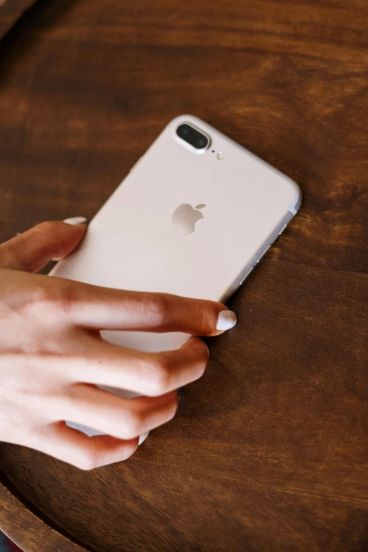 a close up of a person holding a cell phone, pexels, gradient brown to white, on a wooden table, back view also, square