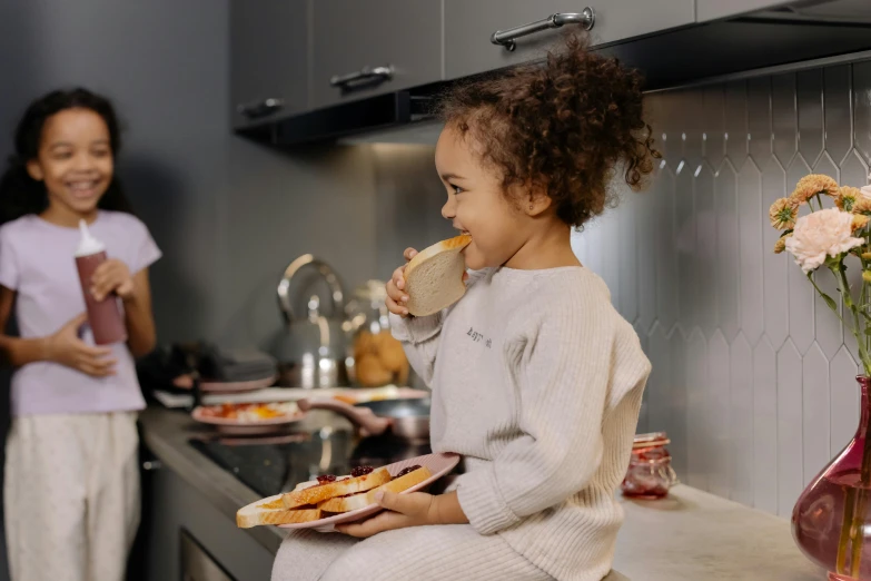 a little girl sitting on a counter eating food, by Emma Andijewska, pexels contest winner, eating garlic bread, avatar image, cooking show, comfortable atmosphere