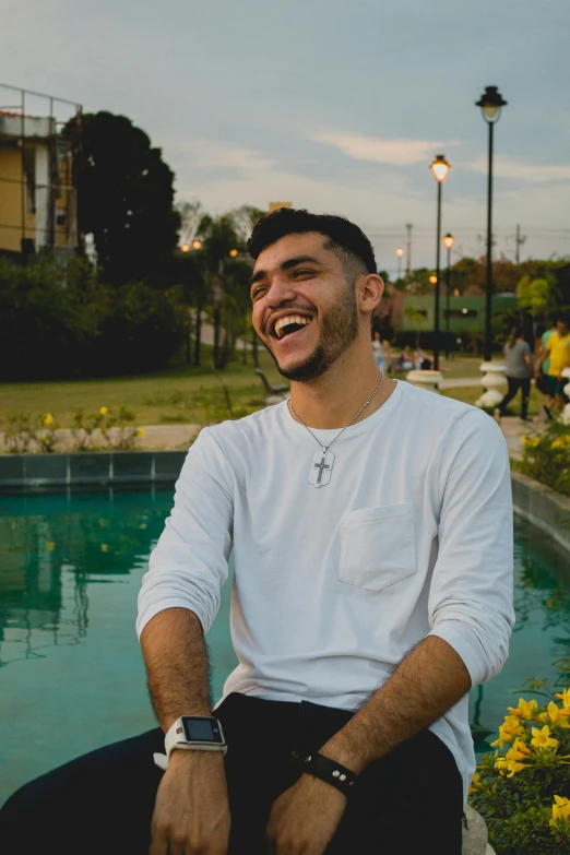 a man sitting next to a swimming pool, an album cover, pexels contest winner, mutahar laughing, in sao paulo, he is about 20 years old | short, profile image