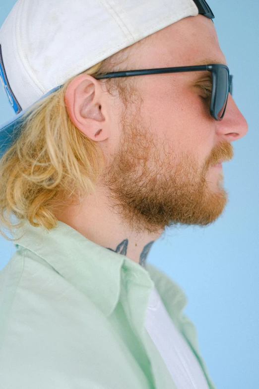 a man with a beard wearing a hat and sunglasses, an album cover, inspired by Cam Sykes, trending on reddit, photorealism, extremely pale blond hair, wearing a light blue shirt, mac miller, close - up profile