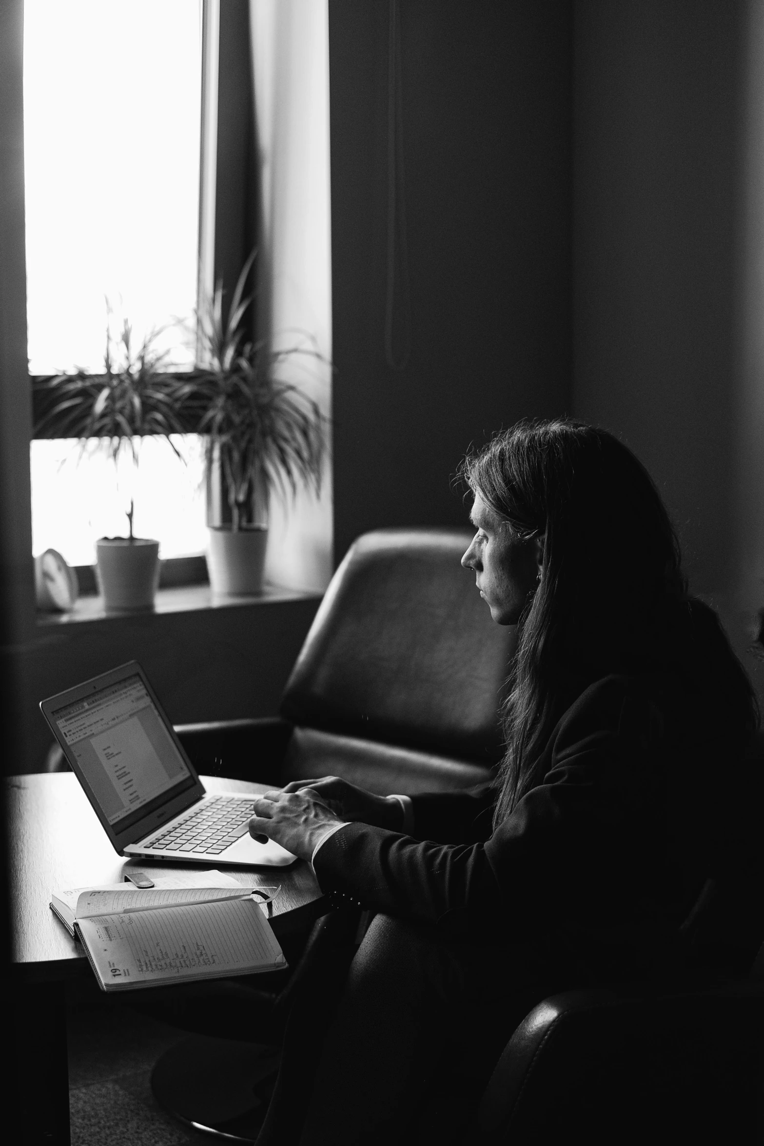 a woman sitting in a chair working on a laptop, a black and white photo, profile image, atmospheric photo, programming, instagram post
