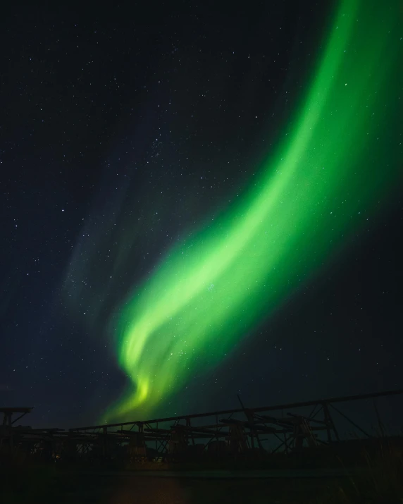 the aurora lights up the night sky over a bridge, pexels contest winner, hurufiyya, waving, black, polar, green sky