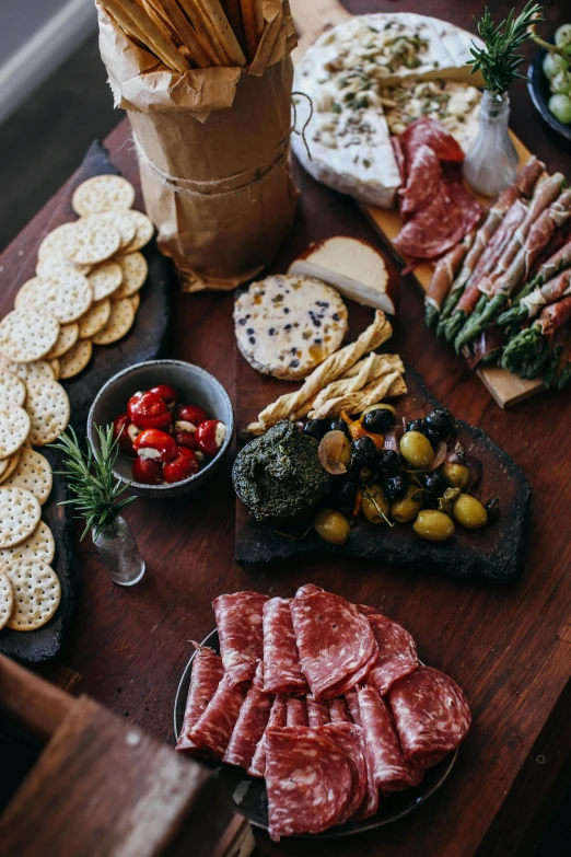 a wooden table topped with lots of different types of food, salami, slate, dwell, australian