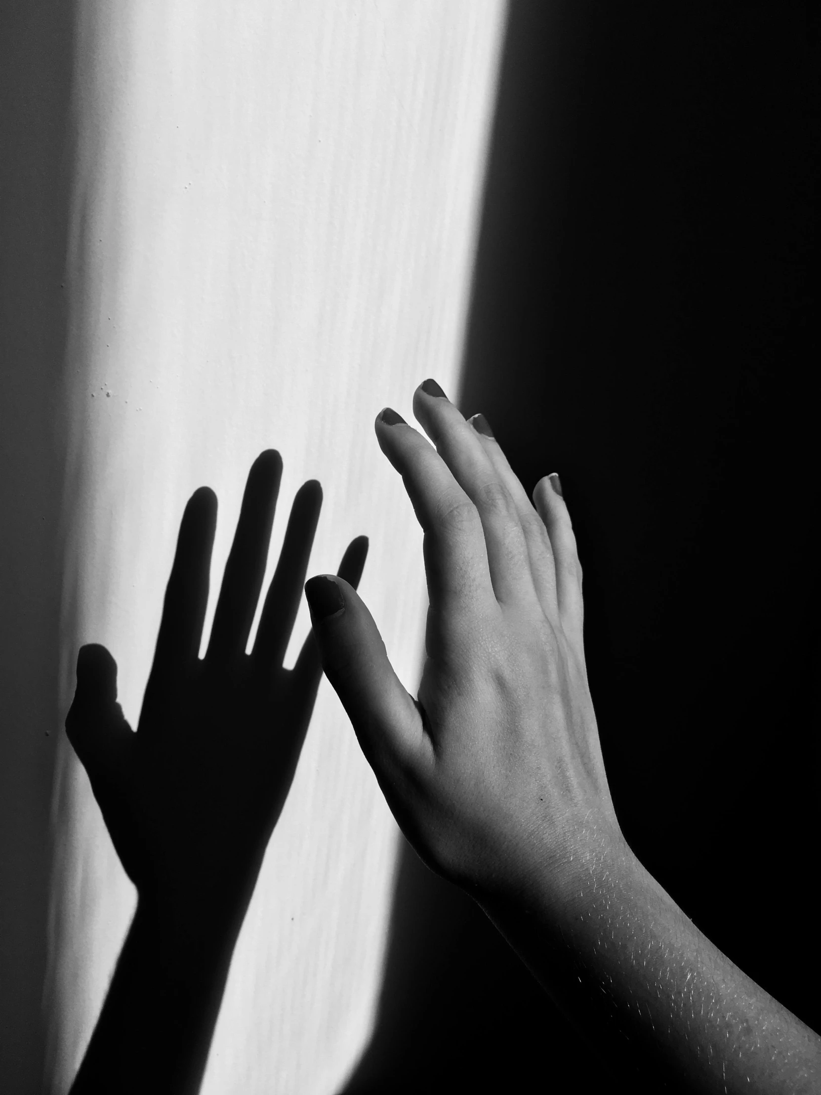 a black and white photo of a person's hands, by Lucia Peka, pexels contest winner, light and space, light rays and shadows, ilustration, wall darkness, touch