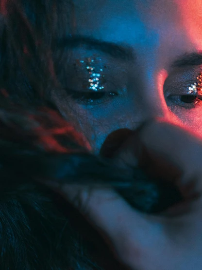 a close up of a person holding a cell phone, an album cover, inspired by Elsa Bleda, holography, stars in her gazing eyes, blue and red lights, shy looking down, glitter