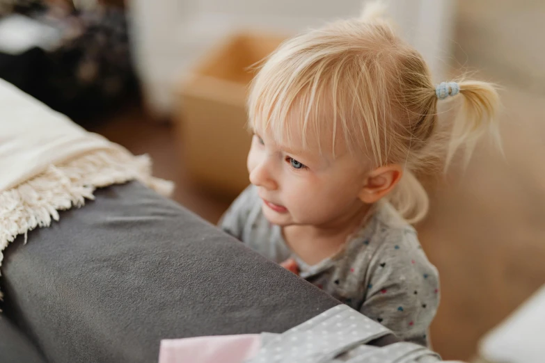 a little girl sitting on top of a couch, pexels contest winner, carefully crafted, bedhead, with a kid, grey