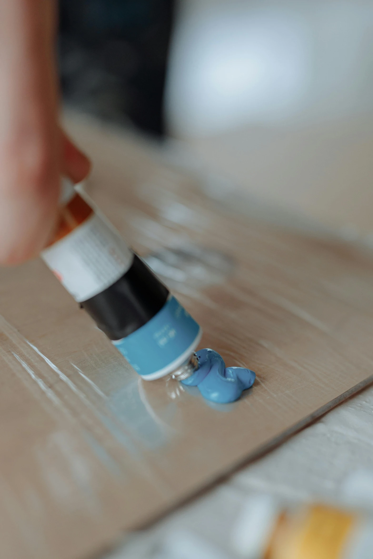 a person using a paint brush to paint a piece of cardboard, a photorealistic painting, inspired by Jan Kupecký, unsplash, lightblue acrylic paintdrip tar, on wood, multi-part, plating