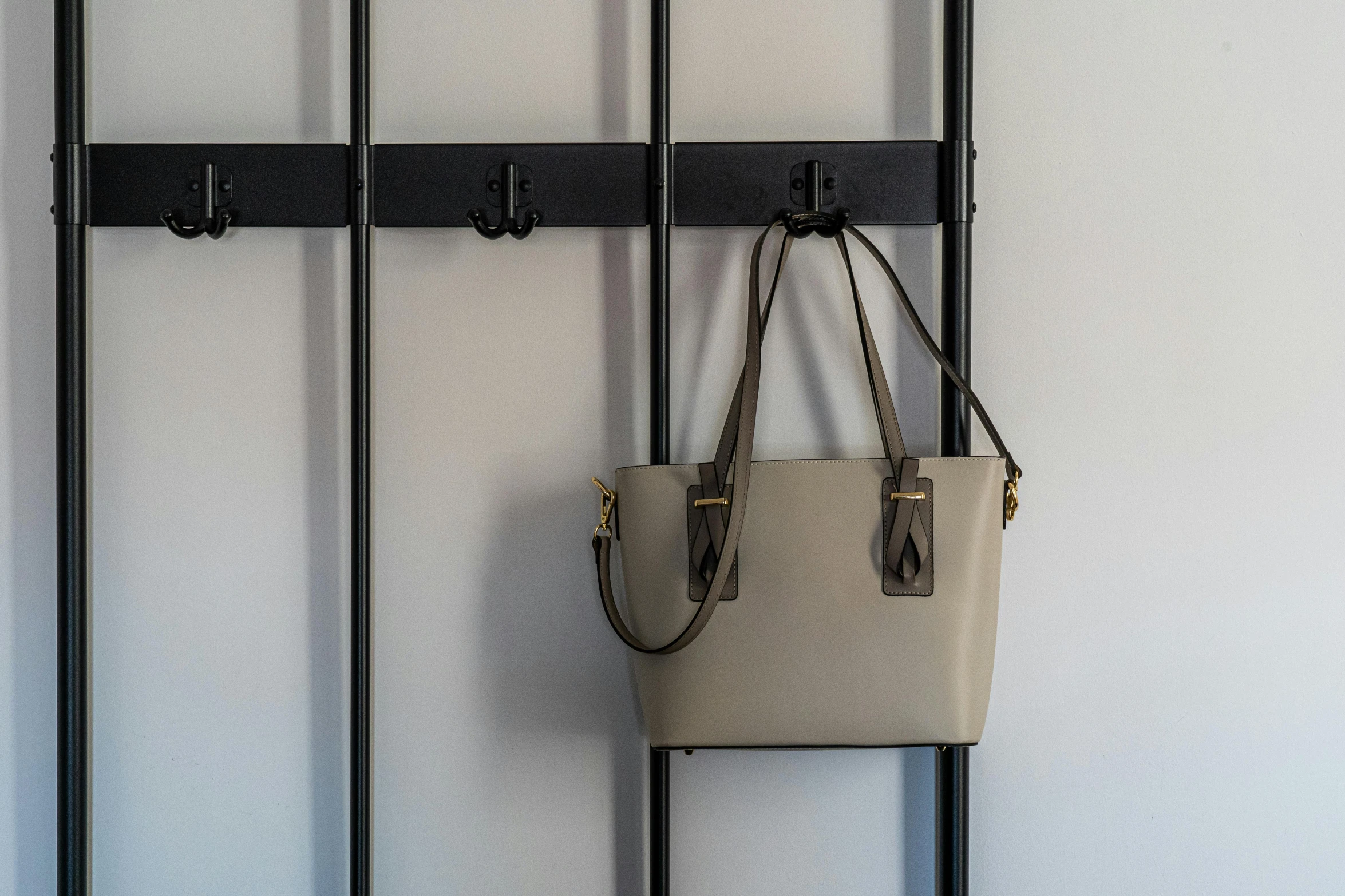 a purse hanging on a wall next to a coat rack, inspired by L. S. Lowry, taupe, small, ladder, padlocks