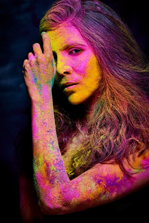 a woman covered in colored powder holding her hand to her face, a colorized photo, color field, kate beckinsale, on a dark background, tendrils of colorful light, fujifilm”