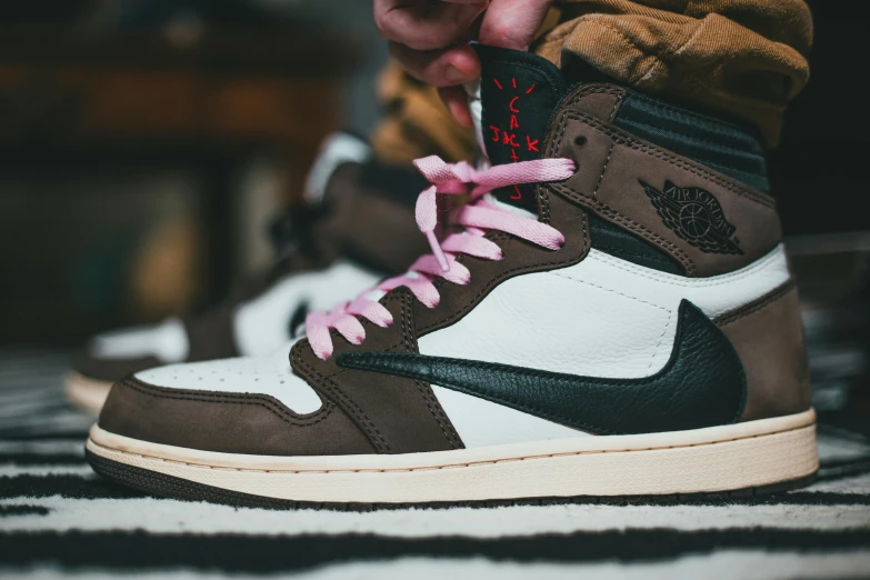 a person tying up a pair of sneakers, an album cover, inspired by Jordan Grimmer, unsplash, sots art, brown and pink color scheme, “air jordan 1, uniform off - white sky, wearing a brown