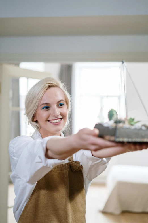 a woman holding a tray with succulents on it, pexels contest winner, smiling young woman, hammershøi, hanging, professional image