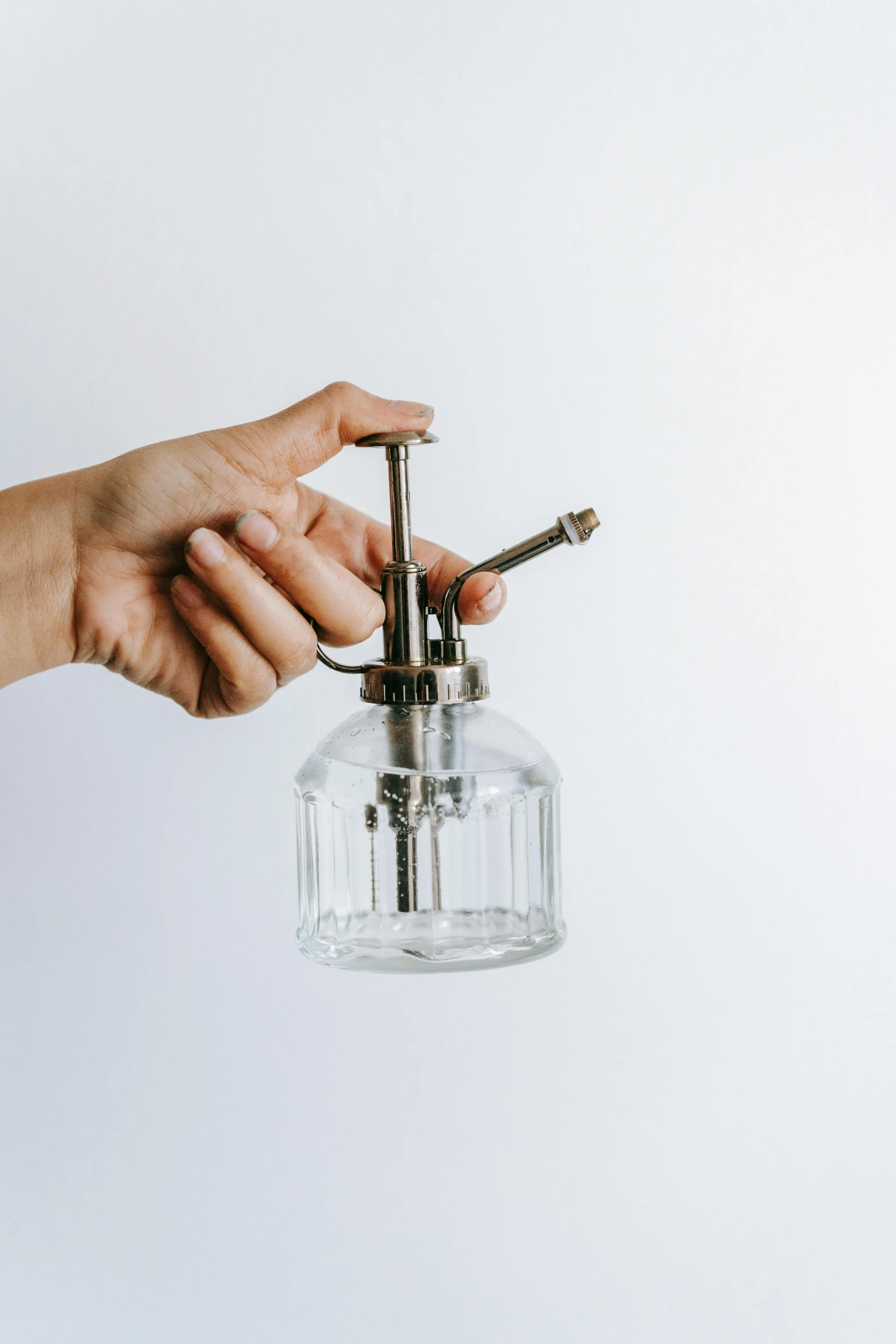 a person holding a glass object in their hand, unsplash, syringe, metal lid, set against a white background, levers