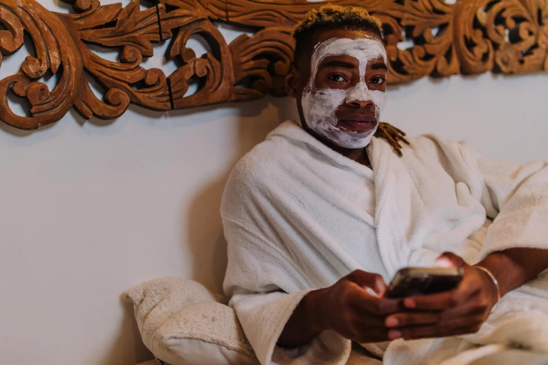 a man in a bathrobe holding a cell phone, trending on pexels, happening, african mask, candy treatments, white facepaint, sexy face