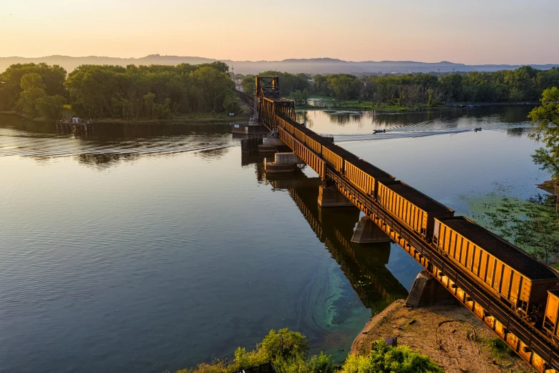 a train traveling across a bridge over a river, by Winona Nelson, pexels contest winner, summer morning light, minn, ultrawide landscape, cornell