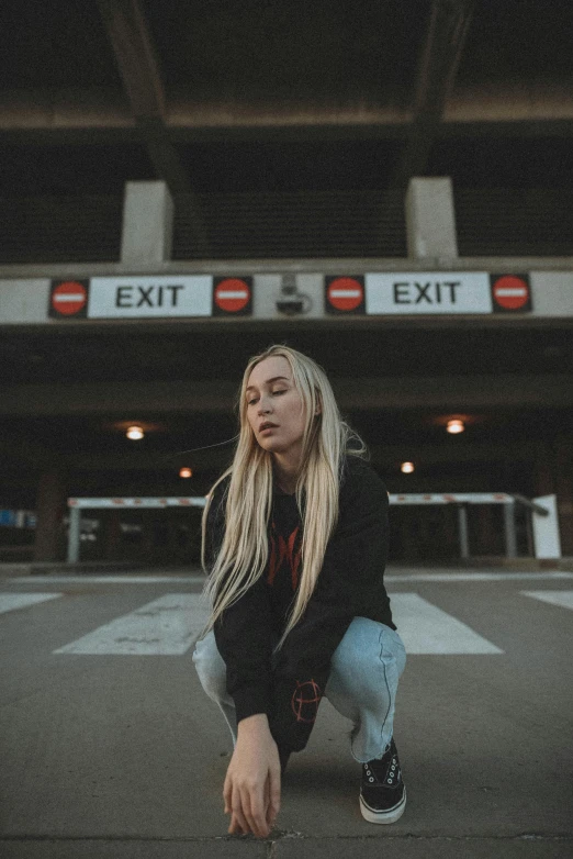 a woman squatting in front of an exit sign, an album cover, inspired by Elsa Bleda, pexels contest winner, portrait of kim petras, airport, low quality photo, intersection