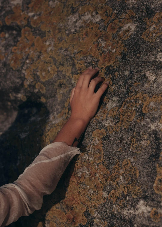 a close up of a person touching a rock, an album cover, inspired by Elsa Bleda, trending on pexels, symbolism, climber, runic arm tattoos, ignant, high angle shot