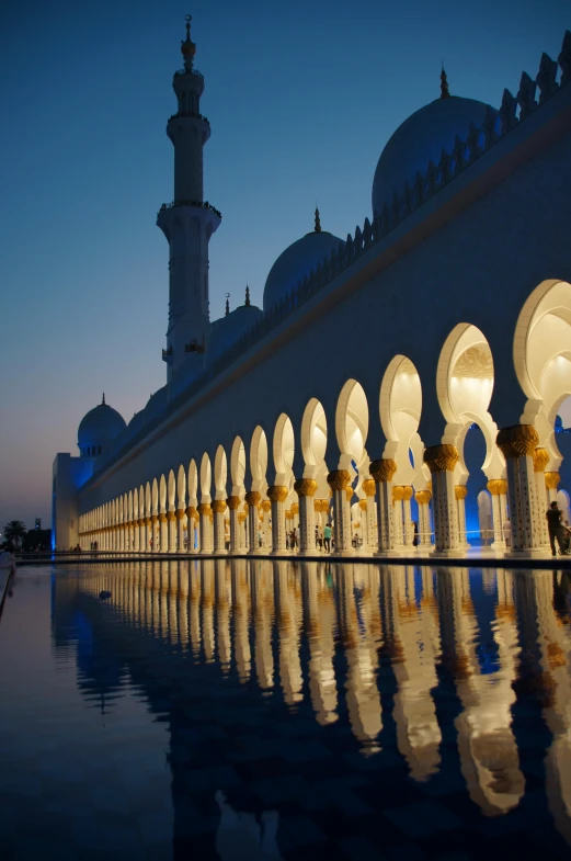 a large white building next to a body of water, inspired by Steve McCurry, arabesque, minarets, evening lighting, gulf, reflects