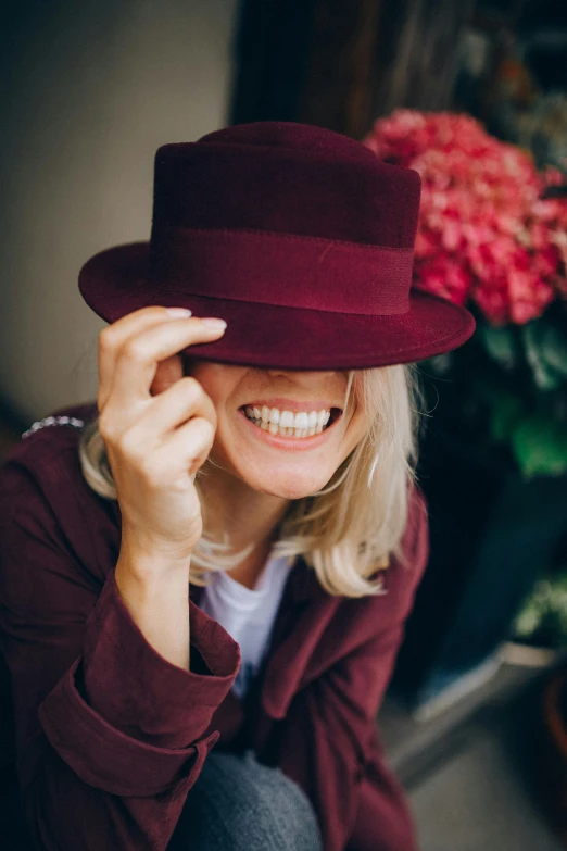 a close up of a person wearing a hat, by Nina Hamnett, elegant smiling pose, maroon, blonde swedish woman, smiling playfully