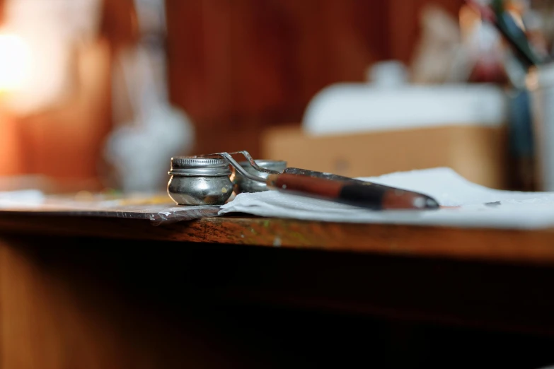 a pair of scissors sitting on top of a wooden table, a still life, unsplash, private press, india ink, with an ashtray on top, thumbnail, close up shot from the side