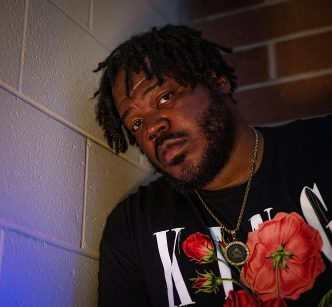 a man with dreadlocks leaning against a wall, an album cover, by Charles Martin, featured on reddit, bust shot, official store photo, nighttime!!, closeup headshot