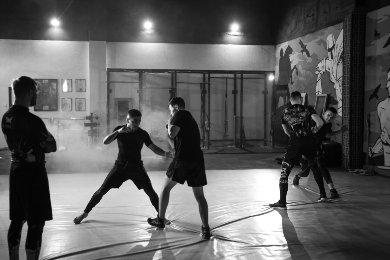 a group of men standing on top of a basketball court, mma southpaw stance, sparring, black & white, in a workshop