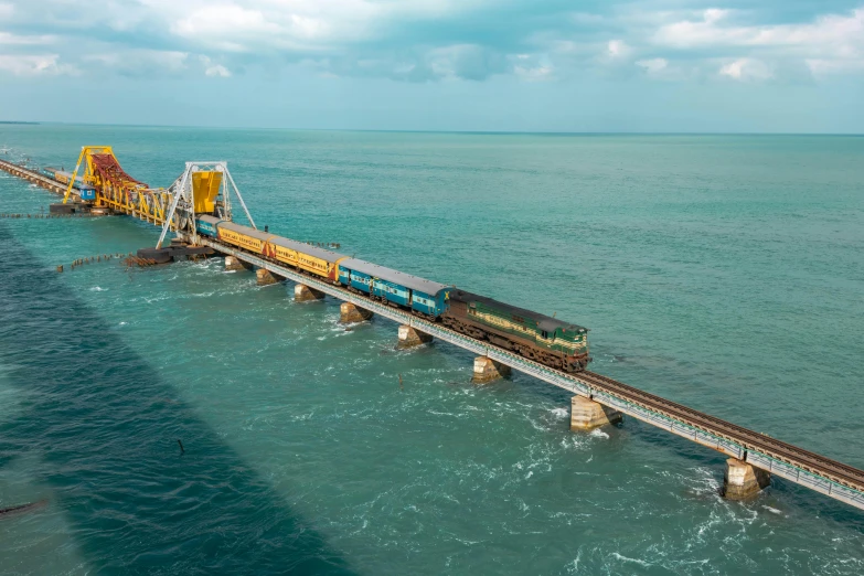 a train traveling across a bridge over a body of water, on the ocean, yellow and blue and cyan, slide show, gulf