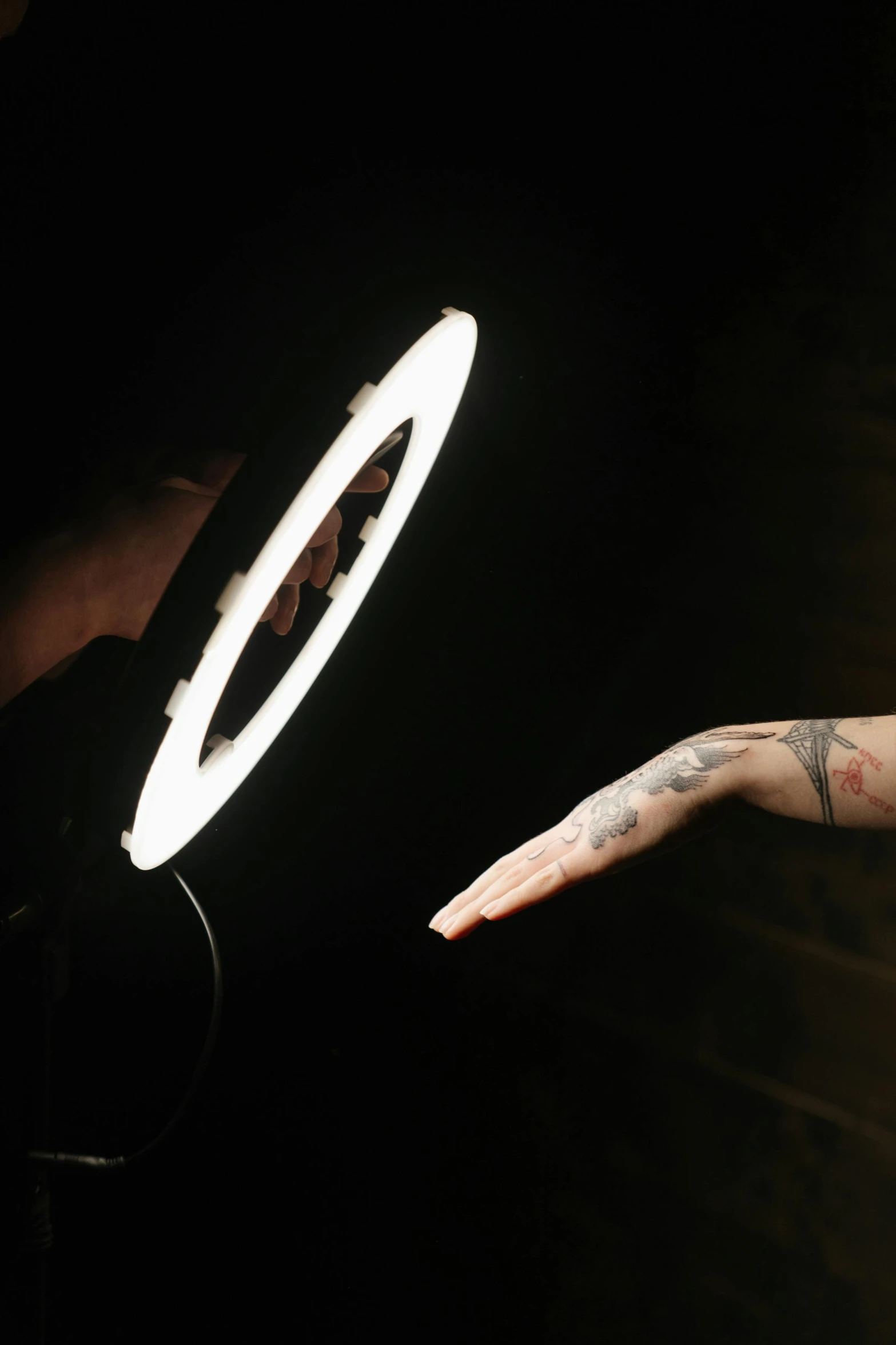 a close up of a person holding a light, a tattoo, by David Begbie, ring light, b - roll, circle, posed