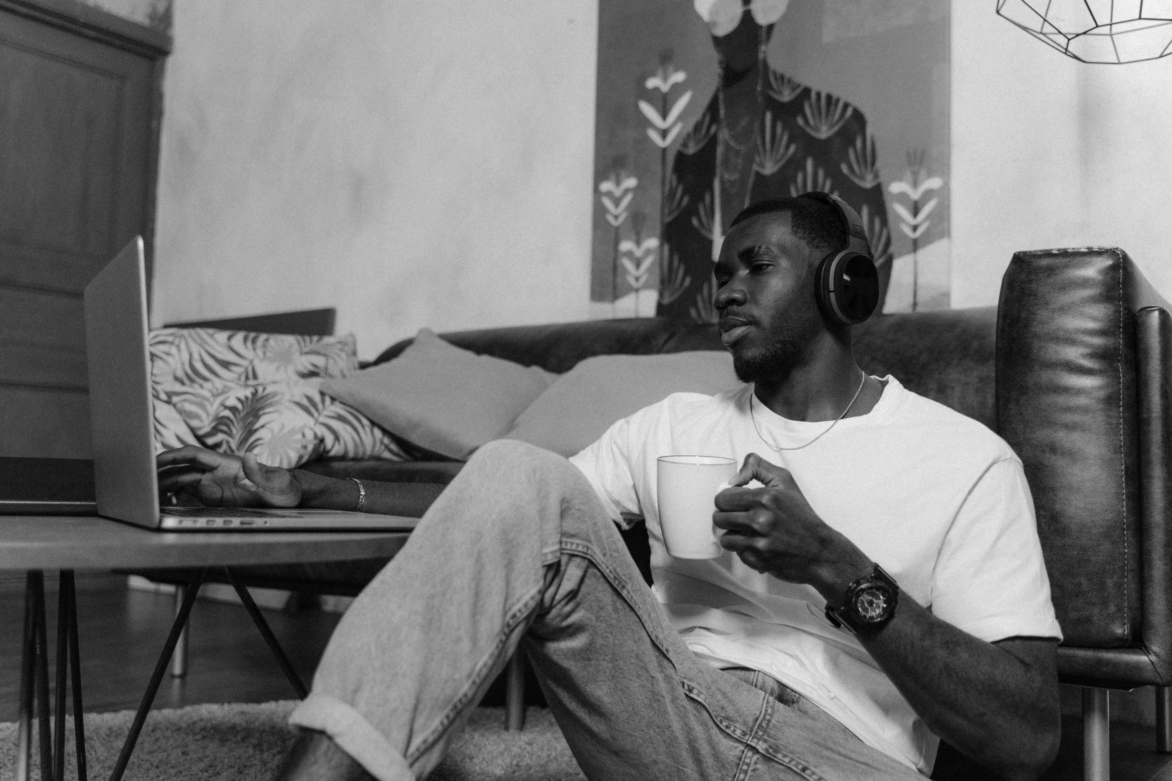 a man sitting on a couch with headphones on, by Felix-Kelly, drinking coffee, man is with black skin, black-and-white, high quality upload