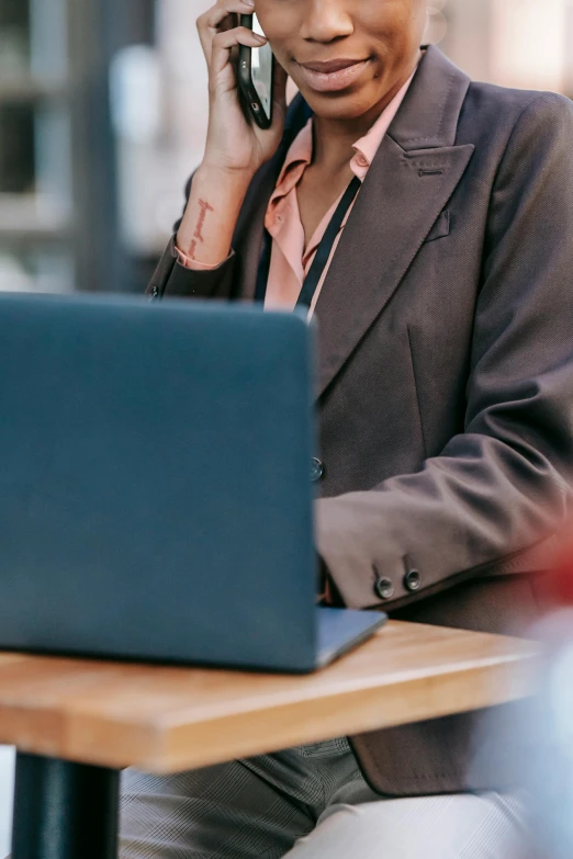 a woman sitting at a table talking on a cell phone, a digital rendering, trending on pexels, laptops, wearing jacket, professional online branding, close up details