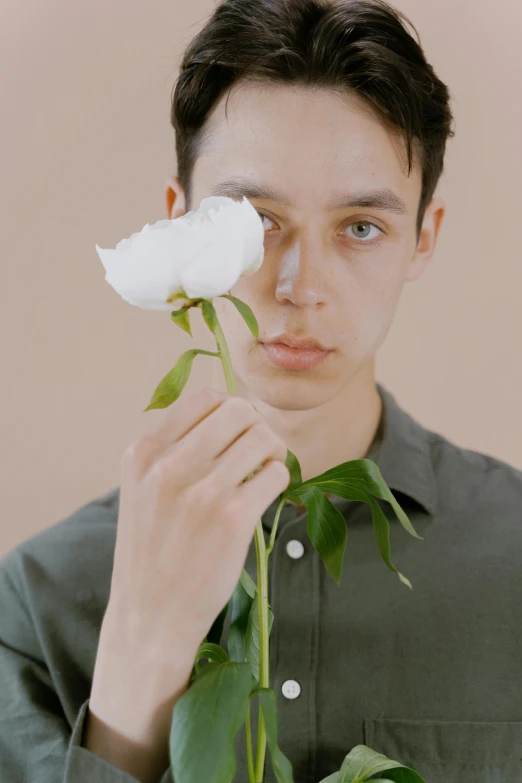 a man holding a white rose in front of his face, an album cover, inspired by Jean Malouel, non binary model, ignant, lean man with light tan skin, flume