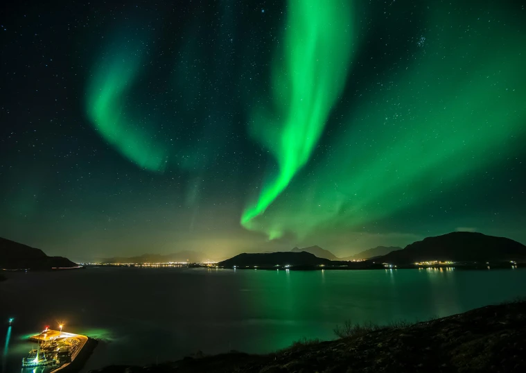 a boat sitting on top of a body of water under a green light, by Julia Pishtar, pexels contest winner, hurufiyya, waves of lights, nordic landscape, distant mountains lights photo, national geographic ”