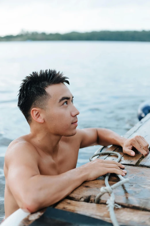 a man sitting on top of a wooden boat, inspired by Liu Jun, pexels contest winner, square masculine facial features, summer swimming party, gemma chen, climber