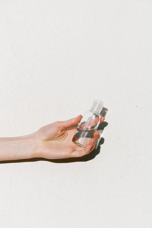 a person holding a bottle of water in their hand, by Nina Hamnett, minimalism, clear makeup, instagram post, smol, transparency