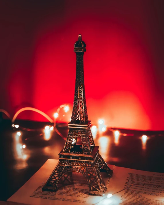 a miniature eiffel tower sitting on top of a book, an album cover, by Julia Pishtar, pexels contest winner, bisexual lighting, red light, a quaint, lgbt