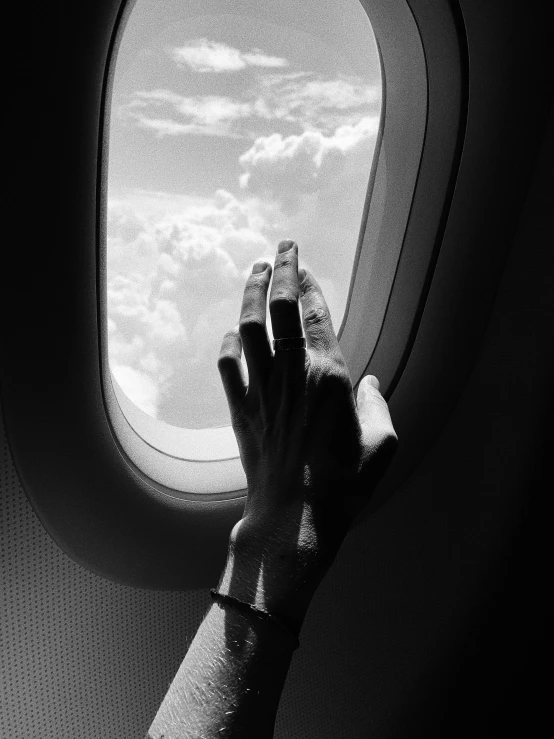 a person's hand reaching out of an airplane window, a black and white photo, by Lucia Peka, surrealism, cinematic. by leng jun, tourist photo, praying, michal mraz