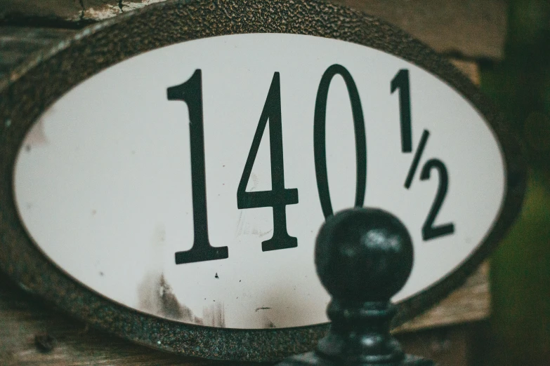 a house number sign sitting on top of a wooden fence, by Adam Rex, unsplash, magnificent oval face, 1820, metal scales, 1 4 4 p