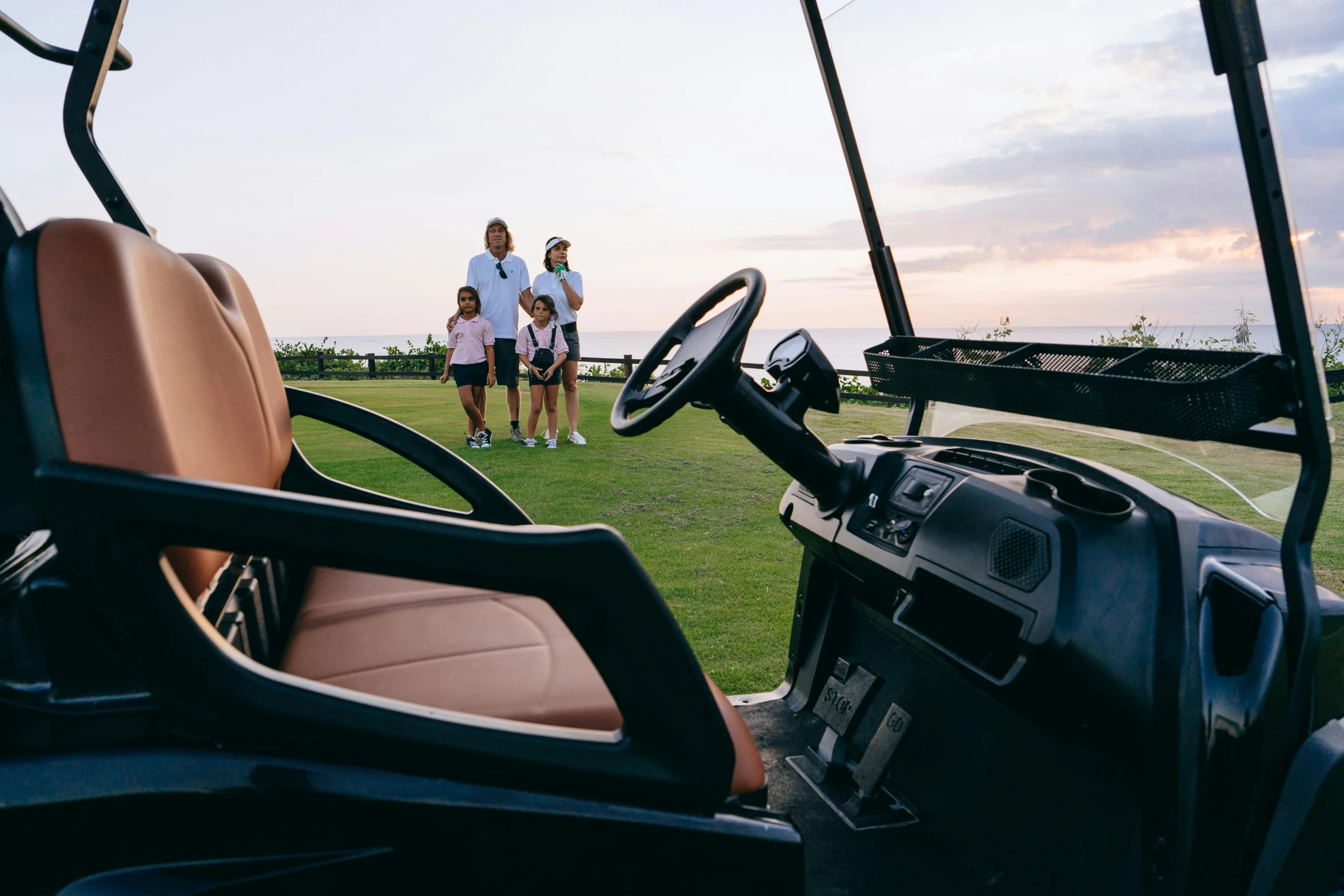 a couple of people standing next to a golf cart, views to the ocean, families playing, side lighting xf iq4, thumbnail