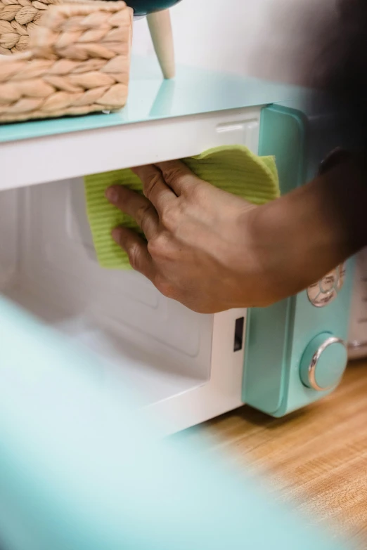 a person cleaning the inside of a microwave, a colorized photo, by Julia Pishtar, unsplash, seafoam green, square, low detail, 15081959 21121991 01012000 4k