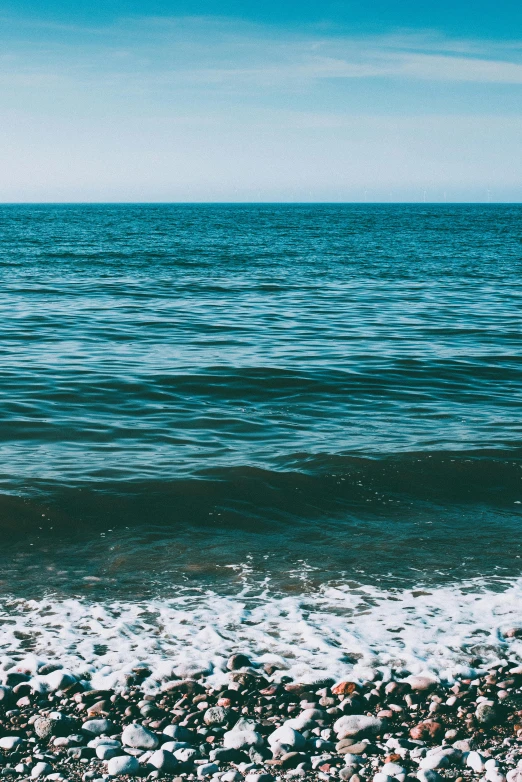 a person riding a surfboard on top of a rocky beach, inspired by Elsa Bleda, trending on unsplash, minimalism, blue crashing waves, water line surface, view of the ocean, gulf of naples